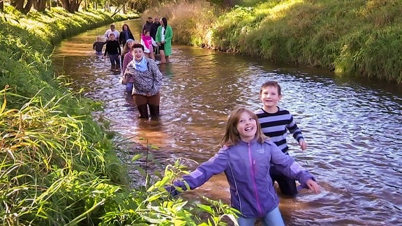 mehrere Menschen laufen durch einen Fluss