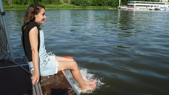 Frau auf einem Boot mit Füßen im Wasser