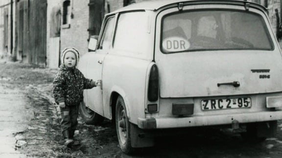 Ein Kind steht an einem Auto.