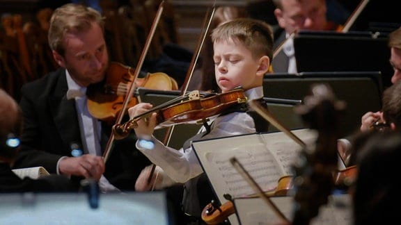 Kind mit Violine bei Orchester-Konzertauftritt 