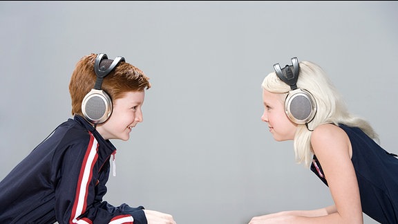 Kinder hören mit Kopfhörern Radio.