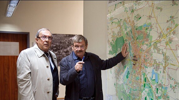 Schmücke (Jaecki Schwarz, links) und Schneider (Wolfgang Winkler, rechts) grübeln vor der Karte über den Fundort der gestohlenen Medikamente.