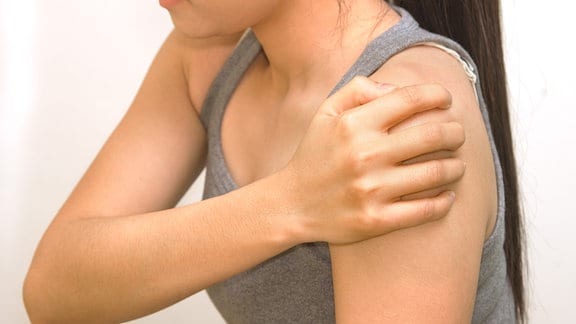 Eine Frau hält ihre schmerzende Schulter