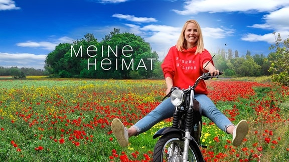 Moderatorin Stephanie Müller-Spirra auf einem Simson-Moped vor einem Mohnfeld mit Sendungslogo "Meine Heimat"