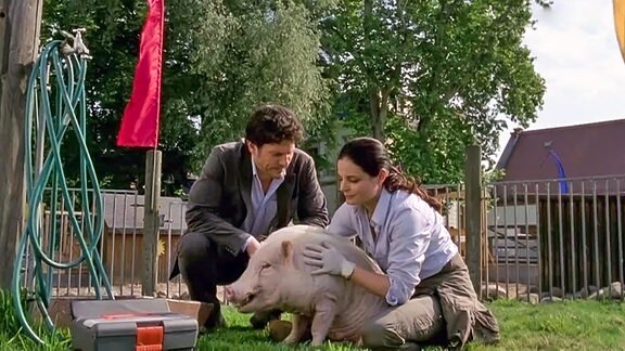 Zwei Menschen halten ein Schwein