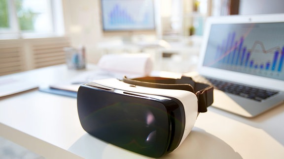 Virtual-Reality-Brille auf dem Schreibtisch mit Laptop in der Nähe.