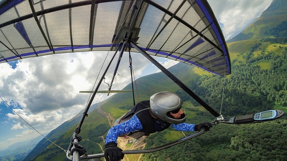 Eine Drachenpilotin fliegt über die Landschaft. 