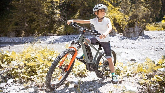 Junge in den Bergen mit einem E-Bike