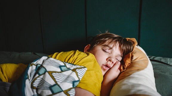 Junge schläft in seinem Bett, gemütlich eingekuschelt.