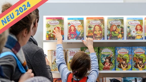 Ein Kind greift 2018 nach Kinderbüchern an einem Stand auf der Leipziger Buchmesse.