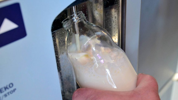 An einem Automaten wird eine Flasche mit Milch gefüllt