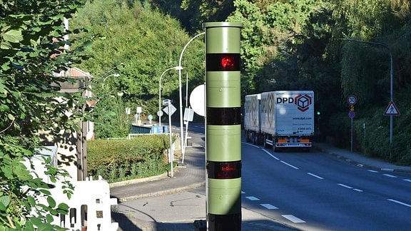Eine moderne Blitzersäule steht an einer Straße. 