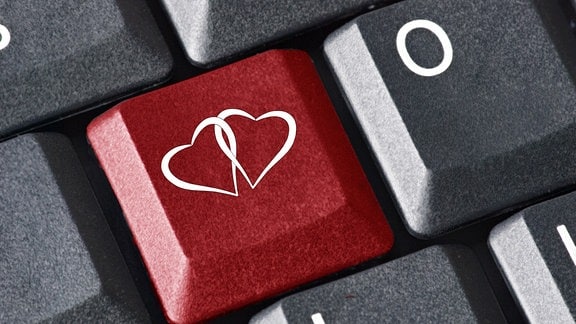 Zwei verschlungene Herzen auf einer roten Taste einer Computer-Tastatur