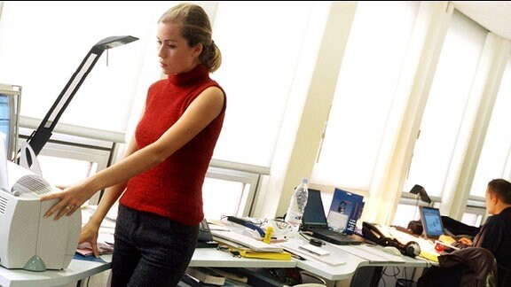 Eine Frau bedient in einem Büro einen Drucker.
