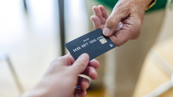 Zwei Hände halten Kreditkarten-Modell