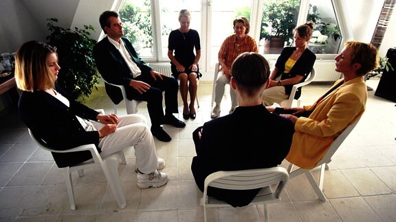 Menschen sitzen in einem Gesprächskreis zusammen.