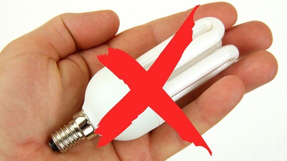 Eine Hand hält eine Energiesparlampe, über der ein rotes Kreuz gezeichnet ist.