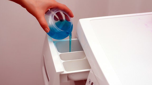 Flüssigwaschmittel wird in eine Waschmaschine gegeben