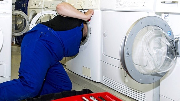 Ein Techniker repariert eine Waschmaschine.