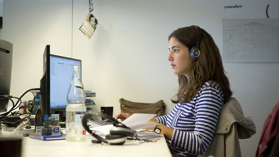 Eine junge Frau sitzt an einem Computerarbeitsplatz. 