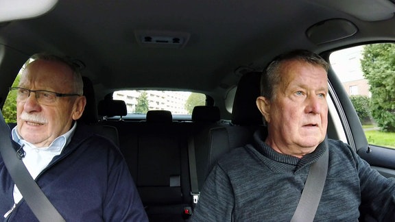Zwei ältere Männer fahren gemeinsam im Auto.