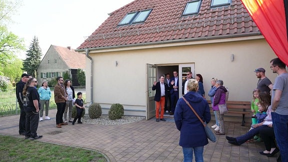 Eine Gruppe Menschen steht vor einem Haus