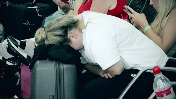 Eine Frau lässt ihren Kopf auf ihren Koffer fallen