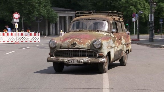 alter verrosteter Opel fährt auf einer Straße