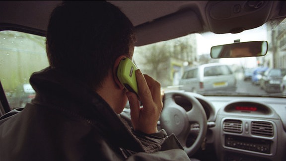 Mann telefoniert im Auto mit altmodischem Mobiltelefon