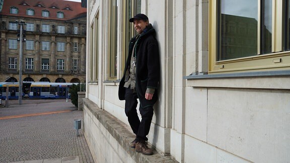 Foto des Künstlers Christoph Blankenburg, der auf einer Hausmauer steht