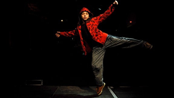 Ein Kind in rotem Hoodie tanzt auf einer Bühne