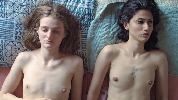 Zwei Frauen liegen nackt auf einem Bett