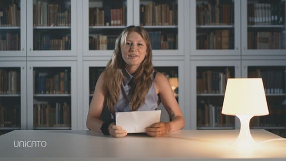 Foto einer weiblichen Person vor einem Bücherregal - Portraitfoto von Charlotte Krafft