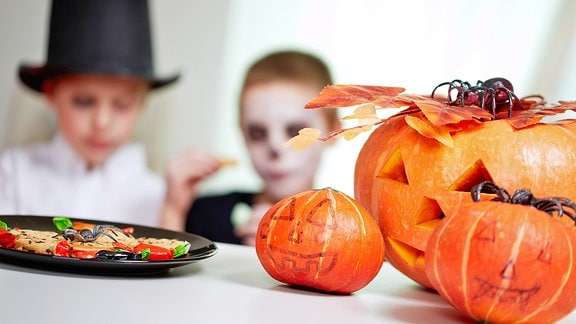 Zwei verkleidete Kinder und Halloween-Kürbisse