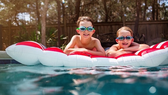 Zwei Kinder auf einer Luftmatratze im Pool