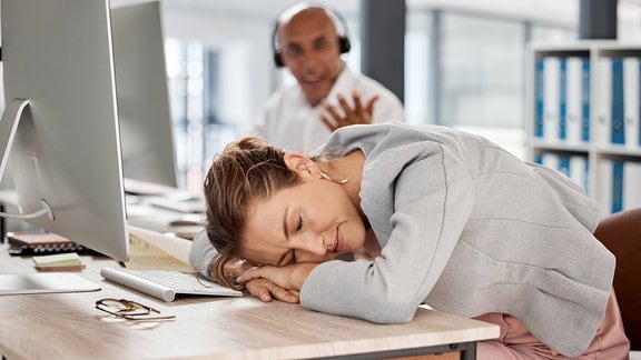 Mitarbieterin eins Callcenters hat schlafend den Kopf auf den Tisch gelegt