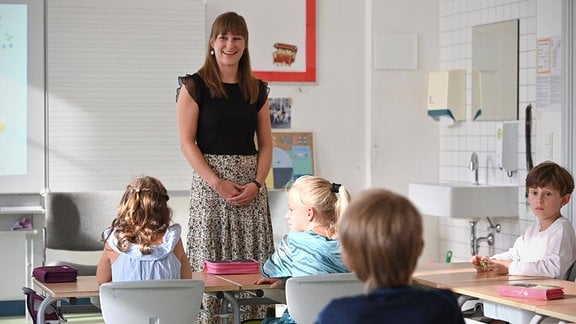 Eine Grundschullehrerin hält Unterricht vor der Klasse.