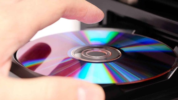 Eine Handy legt eine DVD in einen DVD Player.