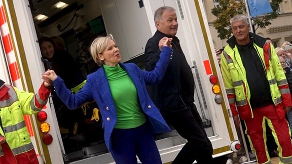 Andrea Kathrin Loewig und Thomas Rühmann hüpfen aus dem Krankenwagen