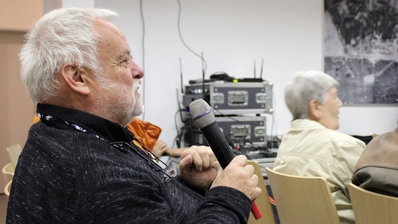Ein Mann mit Vollbart spricht in ein Mikrofon