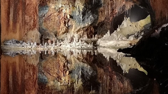 angeleuchtete Felsen mit See in einer Höhle