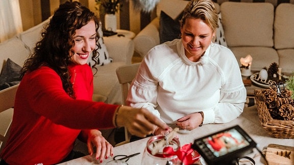 Zwei Frauen basteln in einem Wohnzimmer Weihnachtsdeko