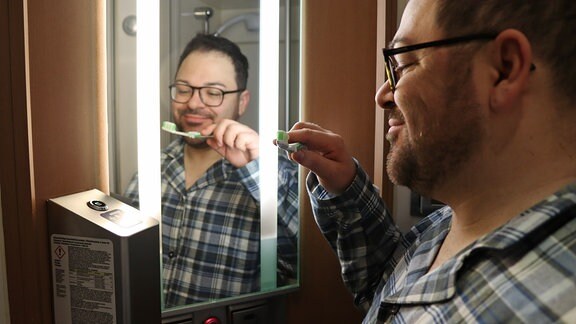 Ein Mann mit Zahnbürste vor einem Spiegel