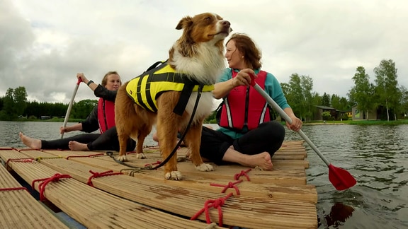 zwei Frauen mit einem Hund auf einem Floß