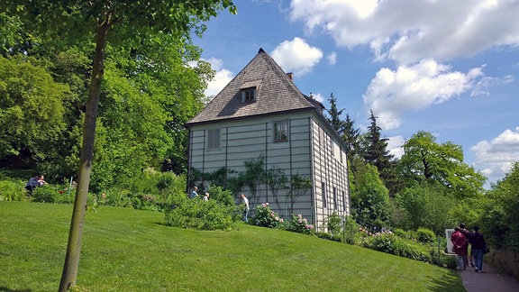 Goethes Gartenhaus in Weimar steht auf einer sonnenbeschienenen grünen Wiese