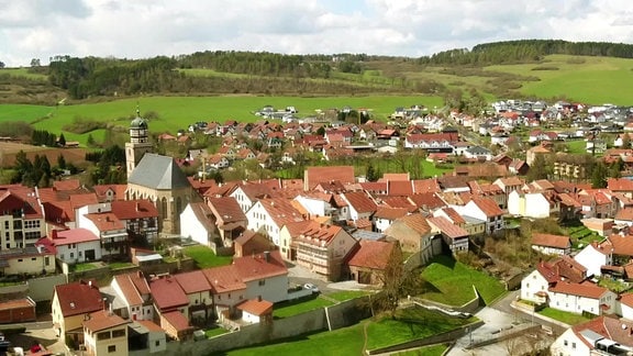 Luftbild der Stadt Geisa mit Kirche unterhalb eines Hügels 