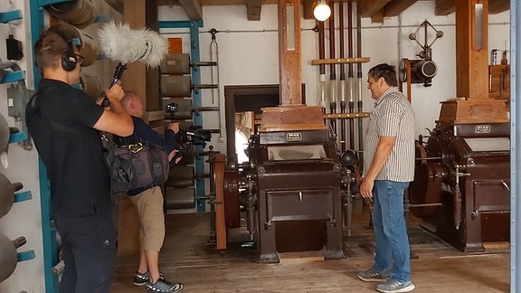 Kamerateam steht mit einem Müller in einer Mühle