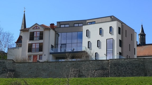 Tourismusbüro Geisa: ein modernes, mehrstöckiges Gebäude oberhalb einer Natursteinmauer