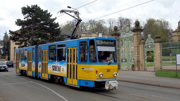 Die Thüringerwaldbahn: Blick auf eine ältere Straßenbahn in gelb und hellblau, die gerade eine Straße entlangfährt.