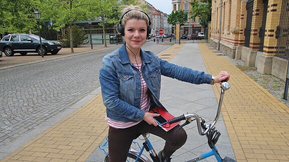 Eine junge Frau mit Kopfhörern auf einem Fahrrad